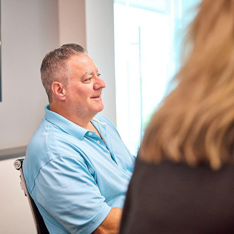 Workers compensation claims process Smiling claims team member seated in a meeting at BerkleyNet workers compensation insurance.