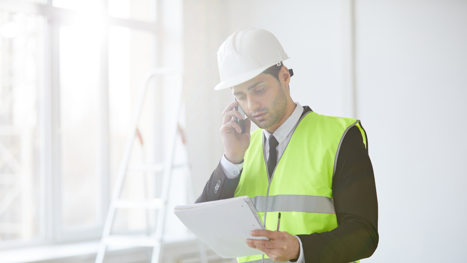 Man wearing a hard hat speaking on the phone, representing prompt claims reporting in the construction industry for workers compensation insurance. 