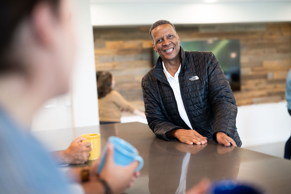 Two BerkleyNet employees smiling while reviewing workers compensation insurance on monitors in an office, a positive workplace culture and team spirit for careers in workers compensation insurance industry. 